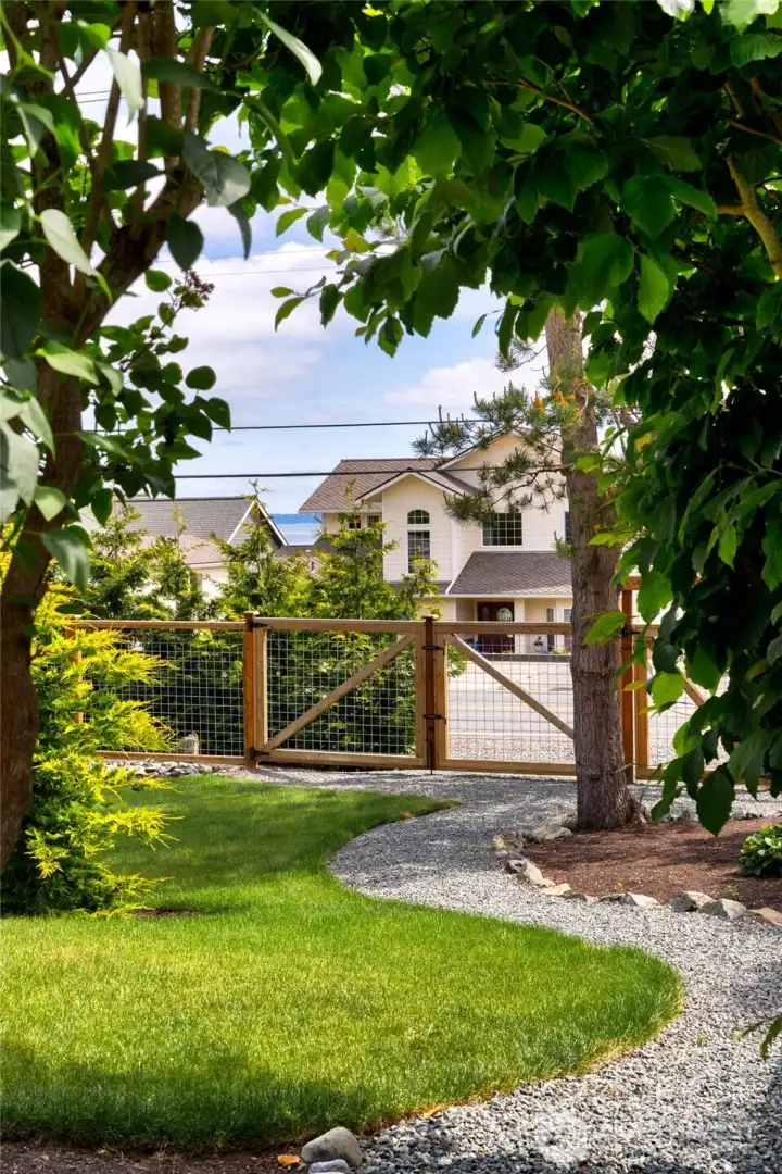 Lush landscaped yard with gated entry and peekaboo water views. Lush landscaped yard with gated entry and peekaboo water views.