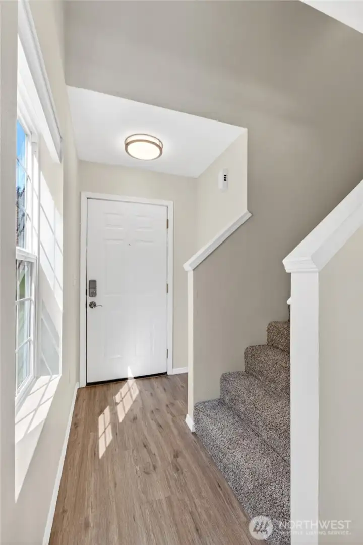 Bright, welcoming entryway with soaring ceiling height, large picture window for natural light, and durable flooring for everyday living. Open staircase design creates an airy first impression and an easy flow into the main living areas.