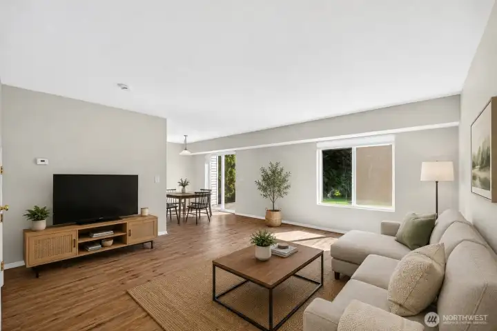 Spacious main living room with oversized windows, updated flooring, and a comfortable open layout designed for both relaxing and entertaining. Bright natural light and peaceful backyard views add to the warm, inviting atmosphere.