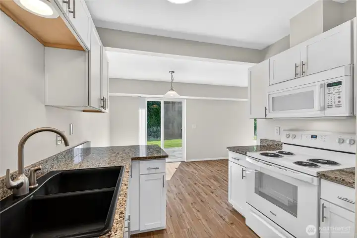 Kitchen opens directly to the dining area and backyard patio, creating an easy indoor-outdoor flow for entertaining and everyday living. Granite counters, updated cabinetry, and abundant natural light give the space a clean, modern feel.