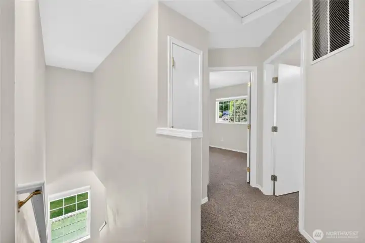 Upper-level landing creates separation between bedrooms while bringing in additional natural light from the stairwell window below. Functional layout offers easy access to bedrooms, storage, and upstairs living spaces.