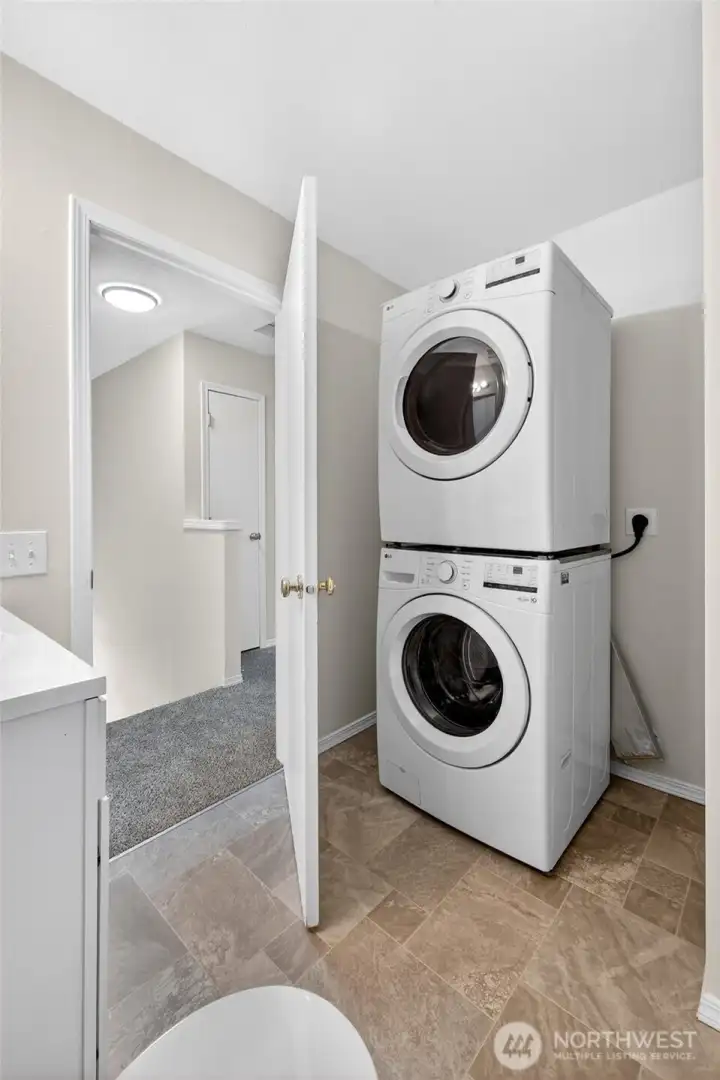 Upstairs laundry area with full-size stacked washer and dryer setup conveniently located near the bedrooms. Functional layout helps simplify everyday living while maximizing usable interior space.