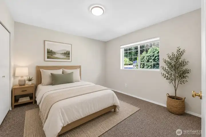Light-filled secondary bedroom with neutral finishes, generous floor space, and large window overlooking mature greenery. Flexible layout works well for guests, home office use, or everyday living needs.