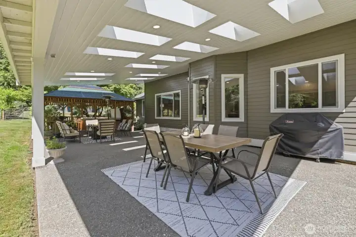 Designed for year-round enjoyment, this expansive covered outdoor entertaining area seamlessly extends the living space outdoors. Featuring a dramatic skylit ceiling, recessed lighting and ample room for dining and gathering, it's the perfect setting for everything from casual family meals to large-scale entertaining. Overlooking the level backyard and complemented by a charming gazebo, this private outdoor retreat offers a rare combination of comfort, functionality, and Northwest lifestyle appeal. Designed for year-round enjoyment, this expansive covered outdoor entertaining area seamlessly extends the living space outdoors. Featuring a dramatic skylit ceiling, recessed lighting and ample room for dining and gathering, it's the perfect setting for everything from casual family meals to large-scale entertaining. Overlooking the level backyard and complemented by a charming gazebo, this private outdoor retreat offers a rare combination of comfort, functionality, and Northwest lifestyle appeal.