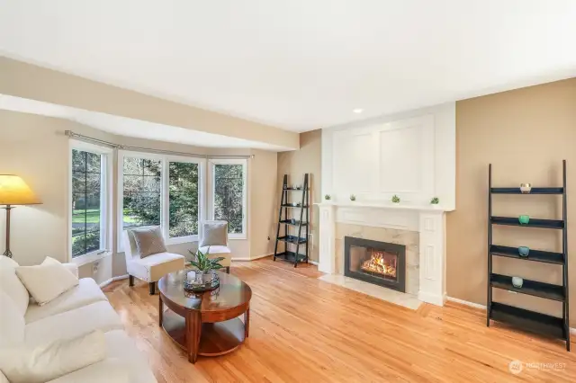 The bright formal living room with large windows and gas fireplace provides ample space for entertainment or relaxation.