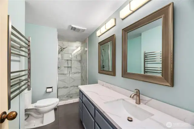 Primary Bathroom  Undermount sink with Calacatta Quartz countertop  Dual decorative mirrors and lighting  AMAZING shower with Italian marble tile and built-in cubbies, dual shower rain  head wand, and custom glass doors  Mirrored medicine cabinet / Tile floors / Heated towel rack  ADA height TOTO toilet