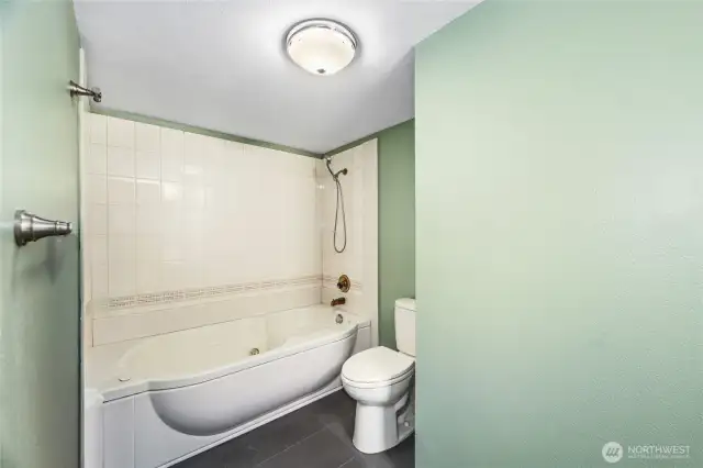 Jacuzzi tub with shower wand and tile surround   Mirrored medicine cabinet / Tile floors