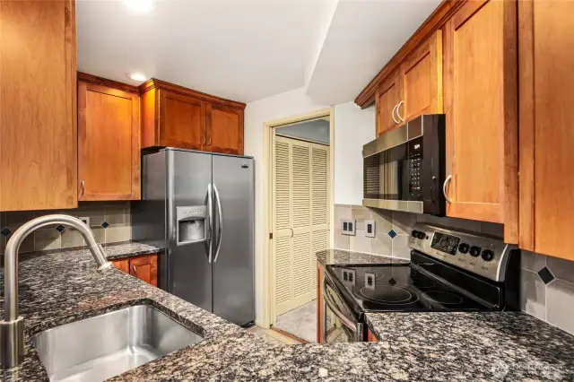 Kitchen   Granite slab countertop / Tile backsplash with glass tile diamond insert   Tile floors match tile backsplash  Stainless undermount sink with Hansgrohe pull out flex wand  Solid wood cabinets with a multitude of upper and lower cabinets & drawers, shelves, cubbies,    cookie sheet cabinet, pull out pantry, spice rack, 3 Lazy Susan’s, and a sink tip out tray