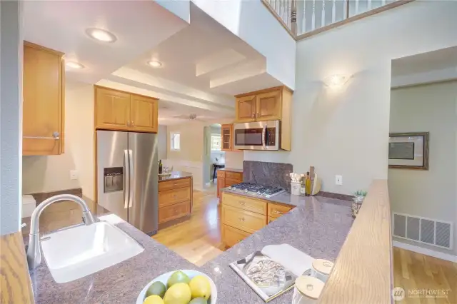 Modern kitchen with gas cooktop, slab counters, a window to the back yard and perfectly situated between the Family Room and Dining Room.