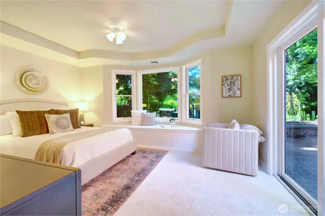 Primary Bedroom with bay window and window seat, brand new carpet, and walk-out to the paver patio in the back yard. Stays cool even without the air conditioner on and the ceiling fan always feels great!