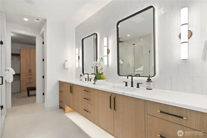 Dual vanity with backlit mirrors, warm wood cabinetry, and designer hardware. Prewired for ceiling speakers plus motion-activated toe-kick lighting.