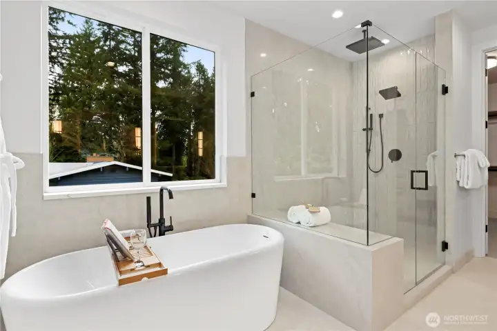 Freestanding soaking tub set beneath a picture window with tranquil treetop views. Walk-in shower has a dynamite bench seat, shampoo niche, and cozy heated-tile floors.