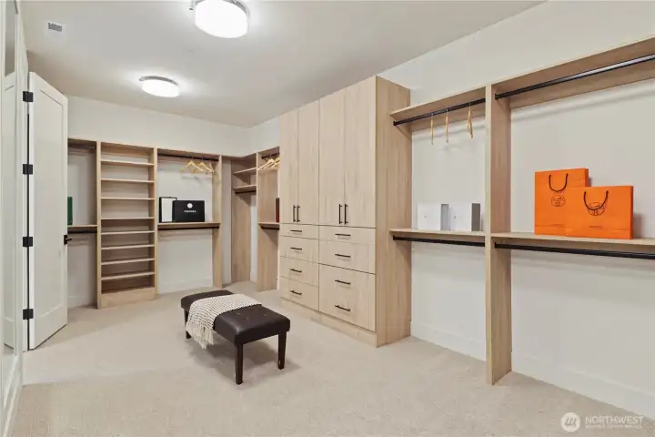 Huge custom walk-in closet with armoire-style cabinets, built-in drawers, open shelving and hanging options, plus a full-length wall mirror.