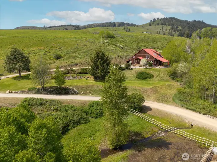 A small seasonal creek meanders through the property below, enhancing the natural landscape, while the home sits privately above with open views, mature landscaping, and easy access from a quiet country road.