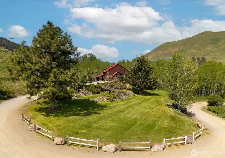 Welcoming approach with landscaped grounds, mature trees, and rail fencing, creating a warm first impression and a true sense of arrival in this peaceful Upper Rendezvous setting.