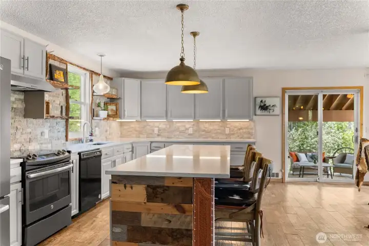 Thoughtfully designed kitchen featuring live-edge stone backsplash, granite counters, and custom leather and wood trim details, complemented by durable laminate flooring and a warm, distinctive finish.