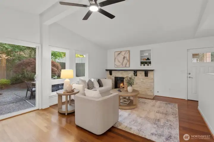 Light-filled living room featuring expansive windows, cozy fireplace and an open, welcoming feel.