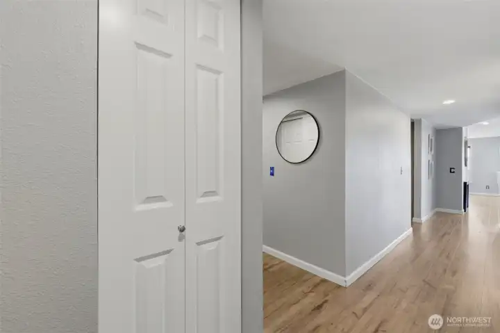 A storage closet sits between the bedrooms. The long hallway on the right of the frame leads to the living and dining areas, the remodeled hallway bathroom, and a large utility/storage room. The hallway to the left leads to the entry and a generous coat closet.