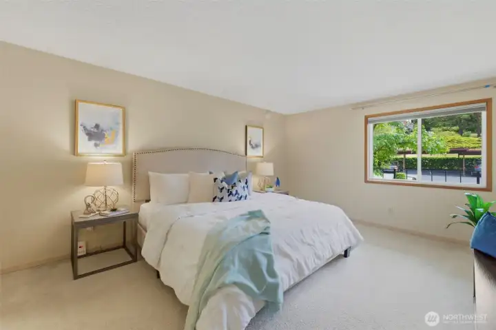 A king sized bed sits flanked by nightstands with plenty of room for additional furniture in this huge primary bedroom.
