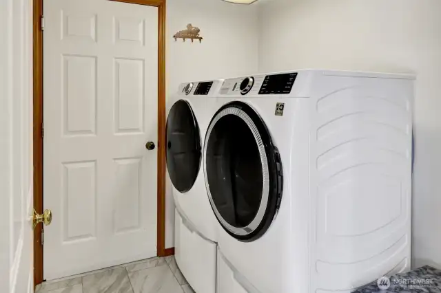 Laundry room located off of kitchen with door leading to garage.   Newer washer and dryer (2021) stays with the home.