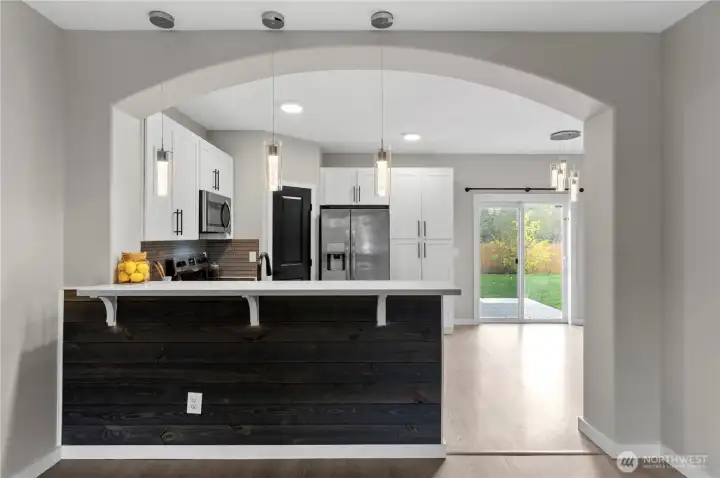 Breakfast bar with quart countertop, open concept kitchen looks out to living room and over dining room