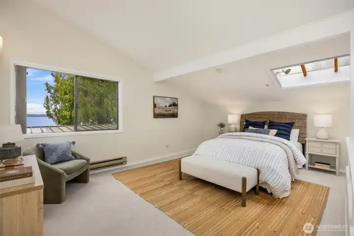 Generously sized loft with a water view,  vaulted ceiling and skylight