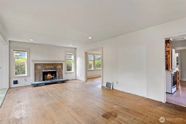 The spacious living room features original oak flooring and cozy a wood burning fireplace with Batchelder tile detail.
