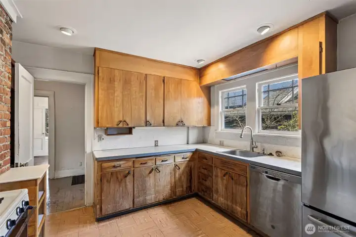 The sunny kitchen with updated windows and newer fridge and dishwasher overlooks an entertainment sized deck.  A good cosmetic update is all it needs.