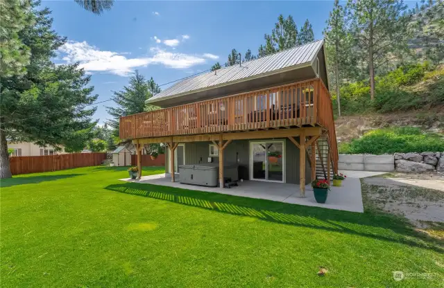 Exterior view of home w/ Upper Level lake view deck, private spa & grassy landscaped yard.