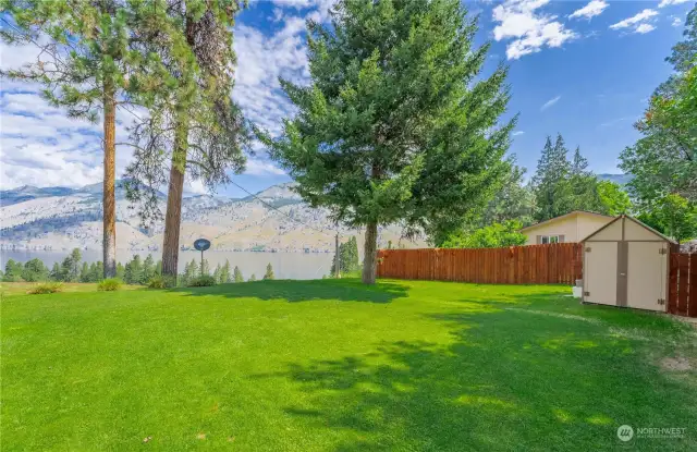 Exterior view of grassy landscaped yard w/ mature shade trees & lake views.