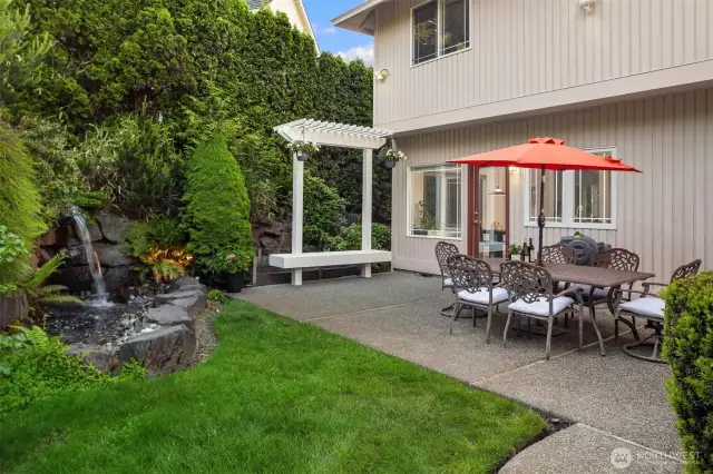 The matured backyard delights with lush landscaping and a serene cascading waterfall.