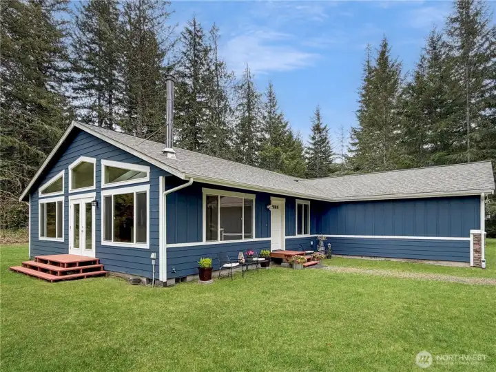 The back of the home showcases the dramatic windows, vaulted roofline, and indoor-outdoor connection — a home designed to soak in the beauty of its 5-acre setting.