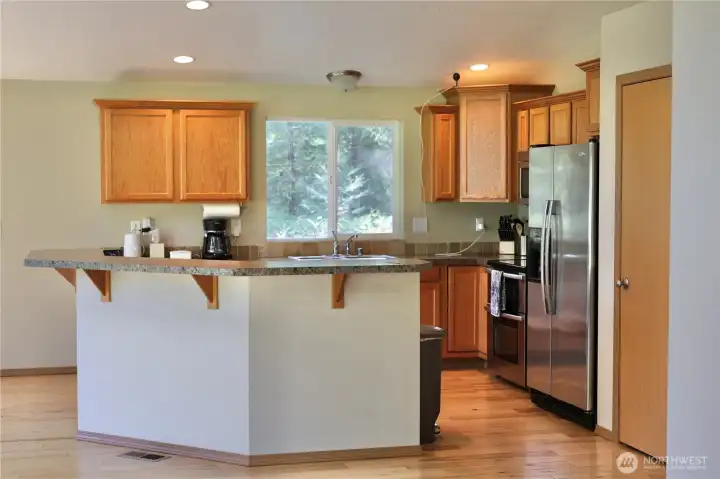 Kitchen with breakfast bar A warm, welcoming kitchen with plenty of counter space, beautiful wood cabinetry, and a natural flow into the living area — perfect for morning coffee, casual meals, and gathering with friends.