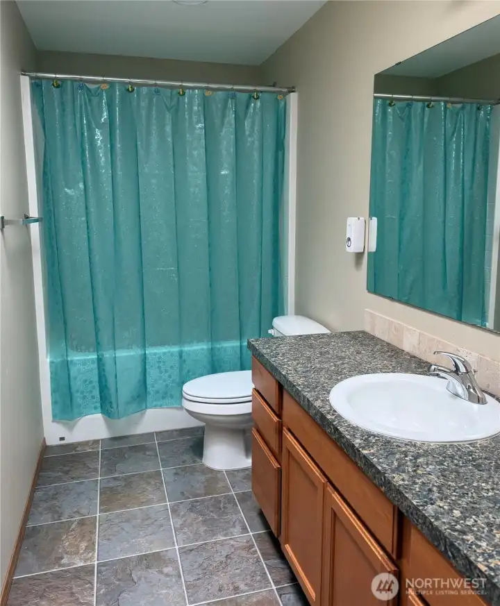 Clean, comfortable, and functional, this full bath offers a fresh neutral palette, tile flooring, and a spacious vanity for easy everyday living.