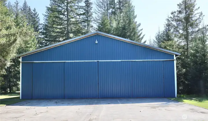 This is the showstopper: a massive hangar with soaring exposed trusses, concrete floor, lighting, and incredible flexibility for aircraft, RVs, boats, equipment, vehicles, or the ultimate dream shop.