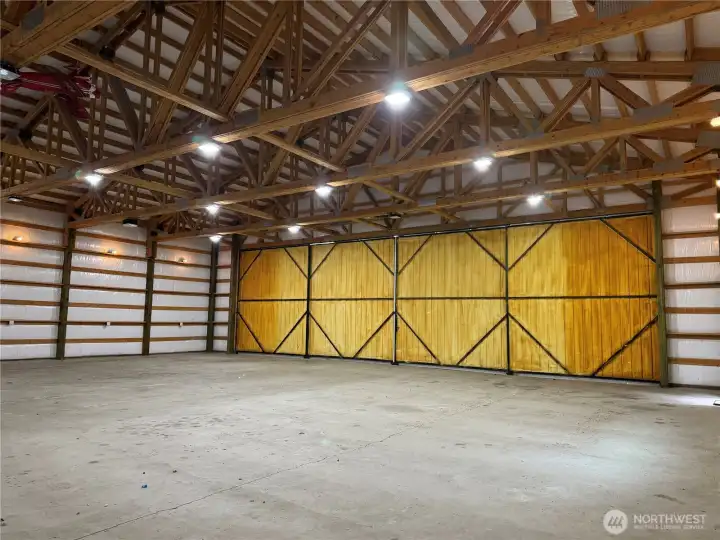 Full hangar door view  Massive hangar doors, dramatic timber framing, and room to move — this is more than storage; it’s a lifestyle feature that sets this 5-acre airpark property apart from anything ordinary.