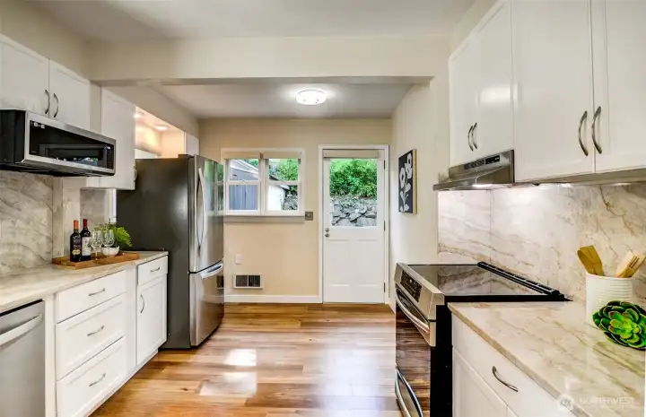 Newly renovated kitchen with granite counters, new appliances and a solid granite backsplash