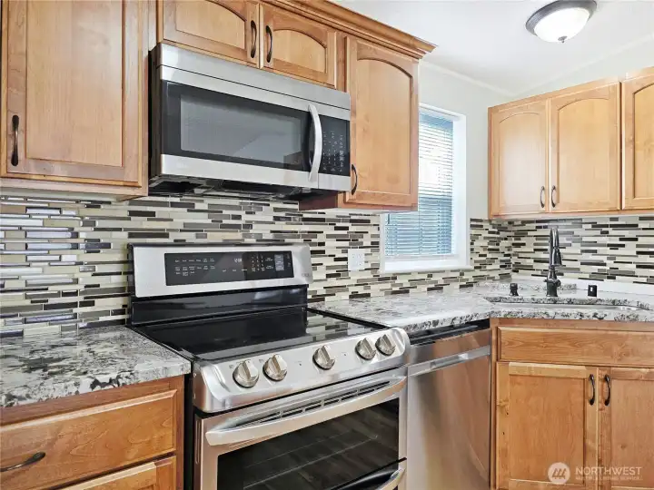 Beautiful custom tile backsplash complements the granite countertops and cabinetry.