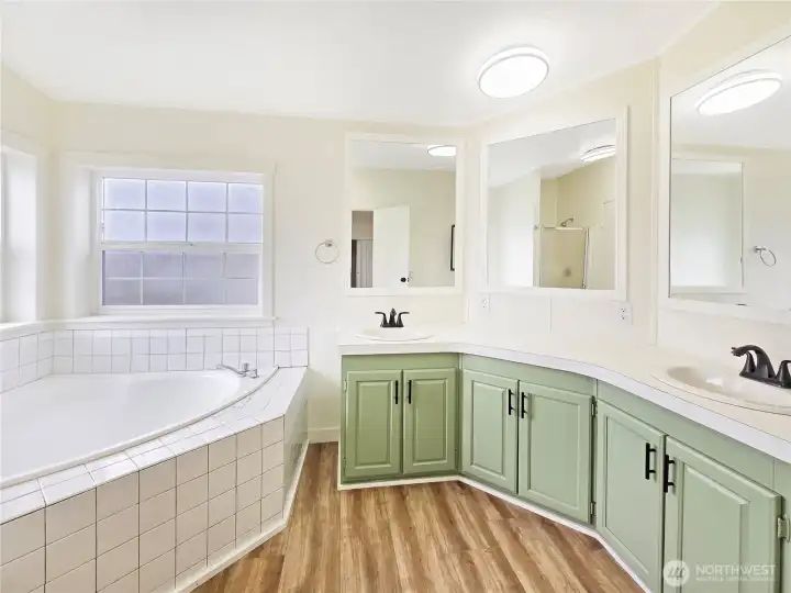 Luxurious five-piece primary bath featuring a corner soaking tub, separate shower, dual-sink vanity, and abundant space to begin and end your day in comfort.