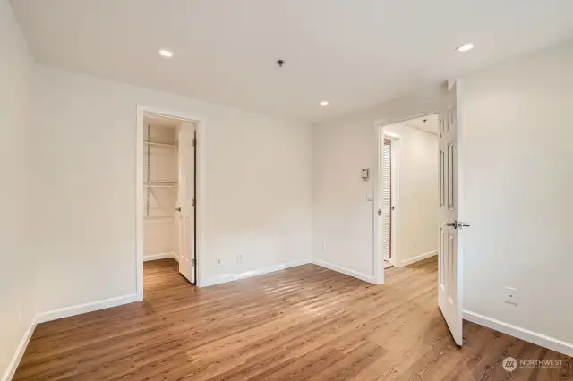 View of the primary bedroom facing the central hall. Well lit with strategic can lighting. Nice sized walk-in closet to stow your gear. The bathroom is right outside the door to the left.