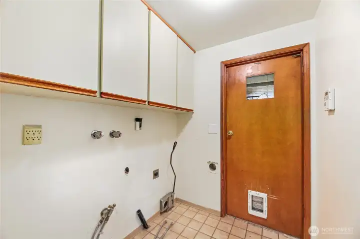 UTILITY/LAUNDRY ROOM  Hookups for Washer and Dryer  Upper cream flat face cabinets with wood trim  Pocket door from interior hall  Door to garage with window and cat door