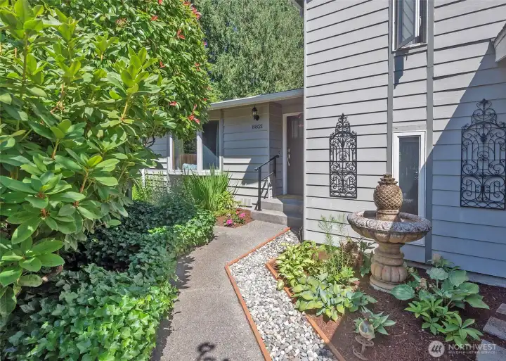 The welcoming front entry is framed by mature landscaping and a tranquil water feature, creating a beautiful first impression and setting the tone for the home's peaceful surroundings.