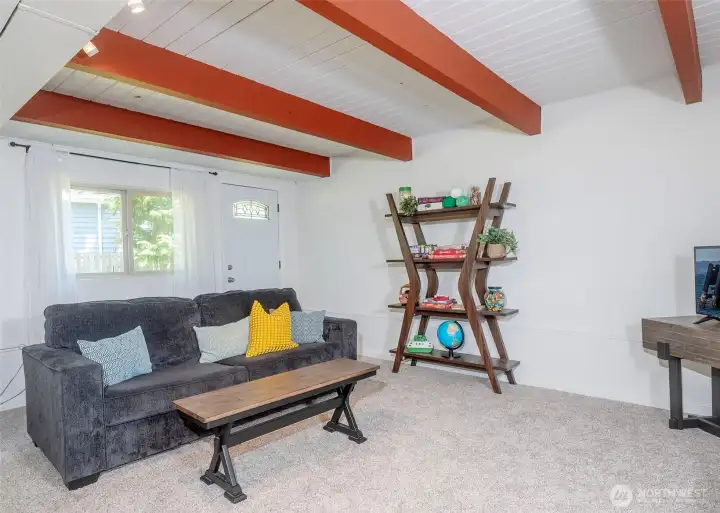 The spacious lower-level recreation room features open beam accents that add warmth and character, along with a convenient door providing direct access to the beautifully maintained backyard.