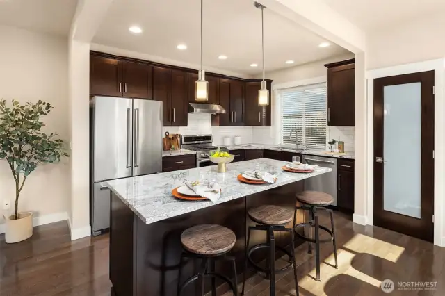 Nicely appointed kitchen features slab granite counters, stainless appliance package, subway tile backsplash and pantry storage
