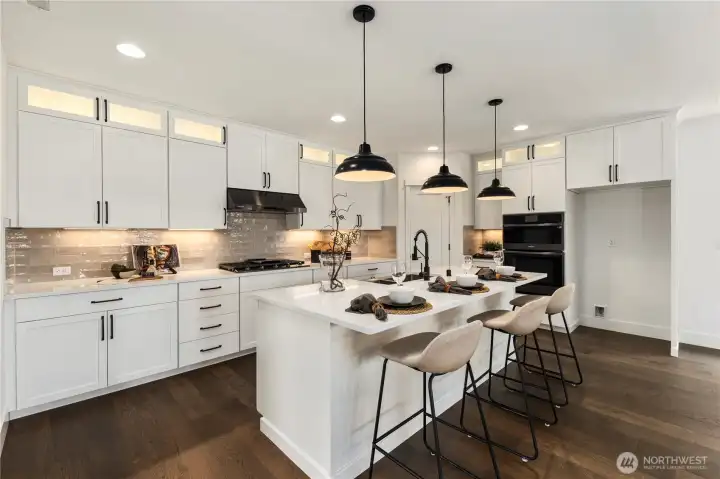 Kitchen: The chef’s kitchen showcases a large quartz island with bar seating, pendant lighting, and abundant counter space. Custom cabinetry, a designer backsplash, and premium stainless appliances create the ideal blend of form and function, perfect for both everyday living and entertaining.  These photos are of the actual, staged home being sold at Foxmoore. However, all photos, renderings, site maps, and floorplans are for visualization purposes only. Plans, colors, building orientation, finishes, home outlook, and other details can and WILL vary.