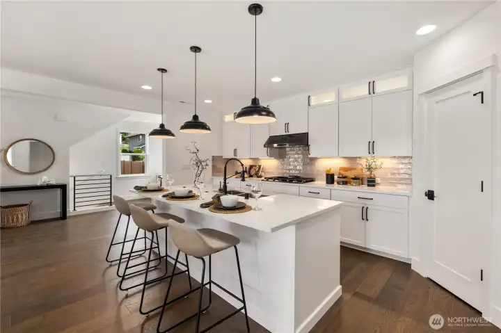 Kitchen View: Sleek island with pendant lighting anchors the kitchen, framed by white cabinetry and premium finishes. The open sightlines keep you connected to the dining and living areas, making this a natural hub of the home.  These photos are of the actual, staged home being sold at Foxmoore. However, all photos, renderings, site maps, and floorplans are for visualization purposes only. Plans, colors, building orientation, finishes, home outlook, and other details can and WILL vary.