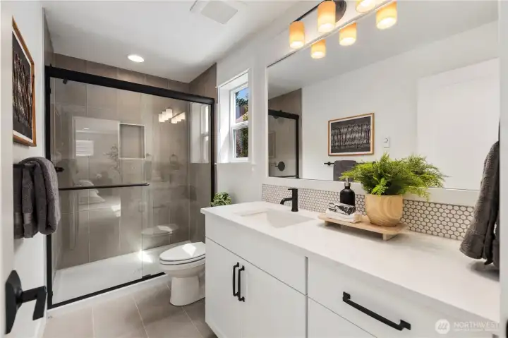 Lower-Level Bathroom: The lower-level bath features a walk-in shower, sleek tilework, and a bright vanity with storage. Conveniently located, it complements the flexible bonus/bedroom space for comfort and privacy.  These photos are of the actual, staged home being sold at Foxmoore. However, all photos, renderings, site maps, and floorplans are for visualization purposes only. Plans, colors, building orientation, finishes, home outlook, and other details can and WILL vary.