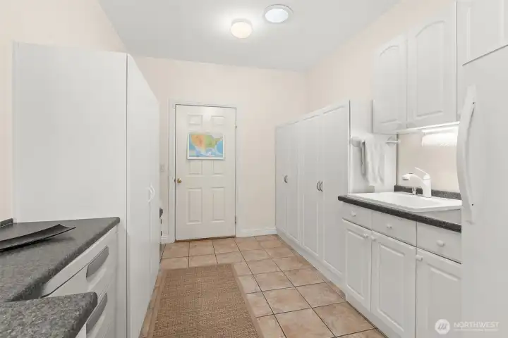 Expansive laundry/mud room has washer/dryer on built-in raised pedestals, handy sink, and so much additional counter space + storage. The door at the far end leads to the garage.