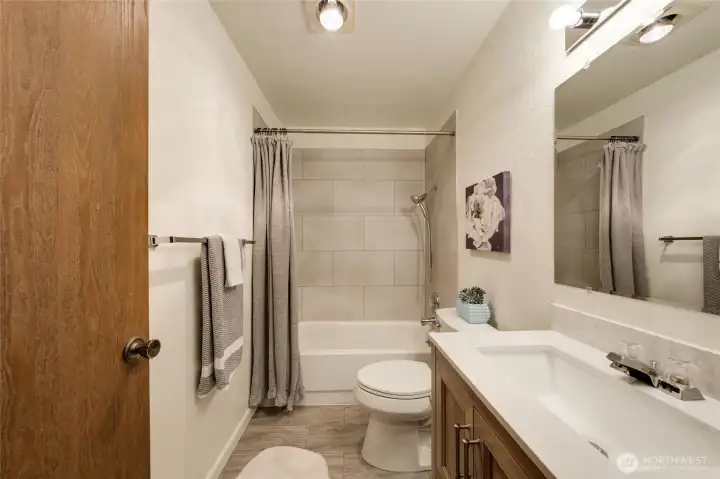 This lovely bathroom has original sturdy tub but features new faucets/fixures, toilet, vanity/sink unit, mirror, vanity light, and new vinyl flooring.