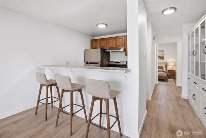 Inviting kitchen bar counter with room for tall stools.  Custom cabinets facing kitchen provide pantry and additional storage. Virtuyally staged.